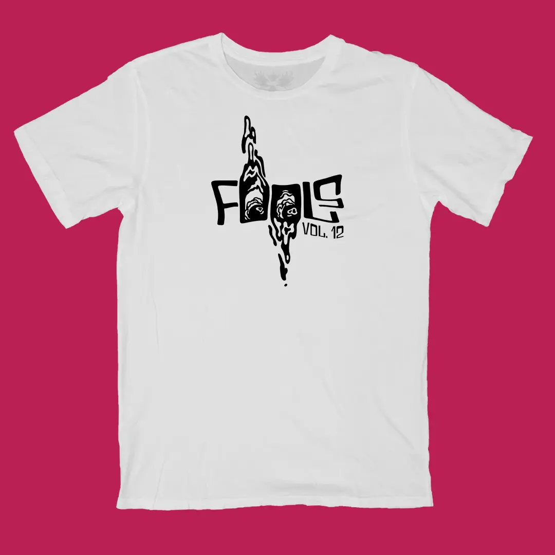 Mockup of the Fools Vol. 12 graphic in black on a white t-shirt.