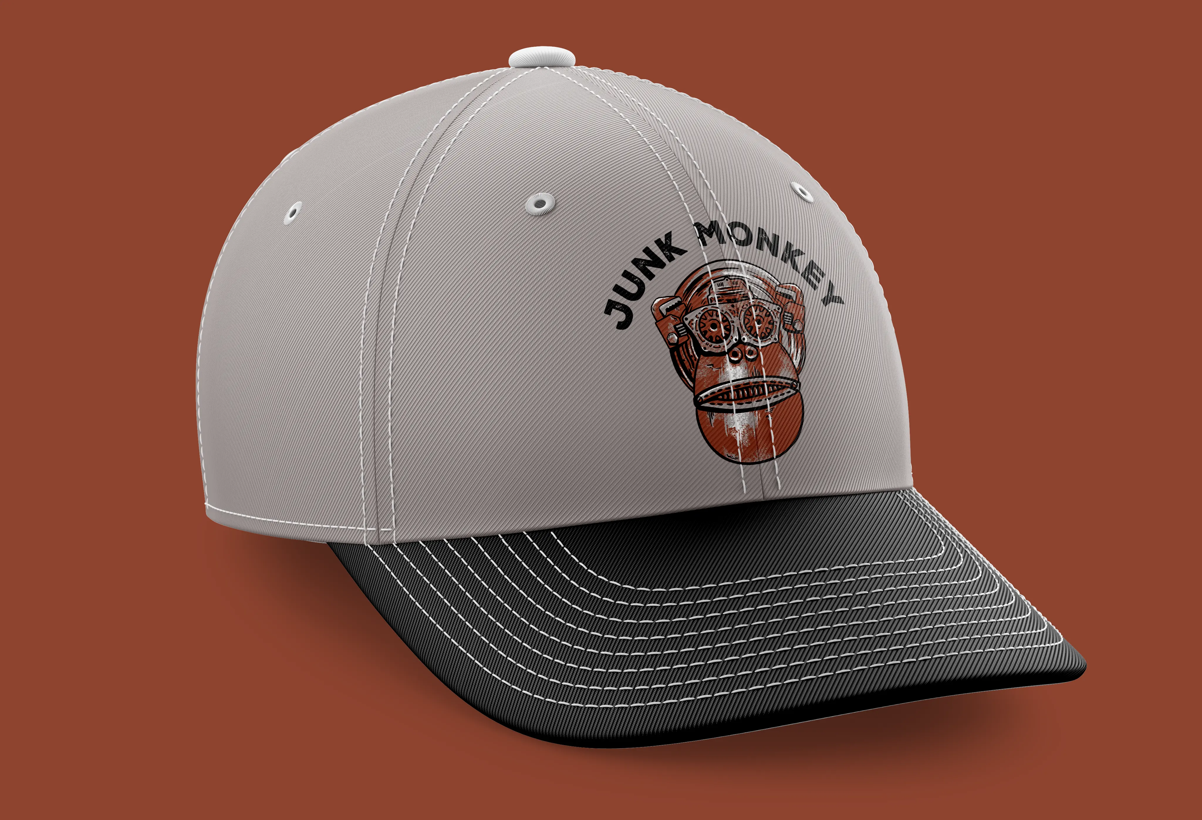 Mockup of the logo on a grey baseball cap with a black bill. Instead of across the bottom, the text arcs across the top 
                        of the Monkey head.