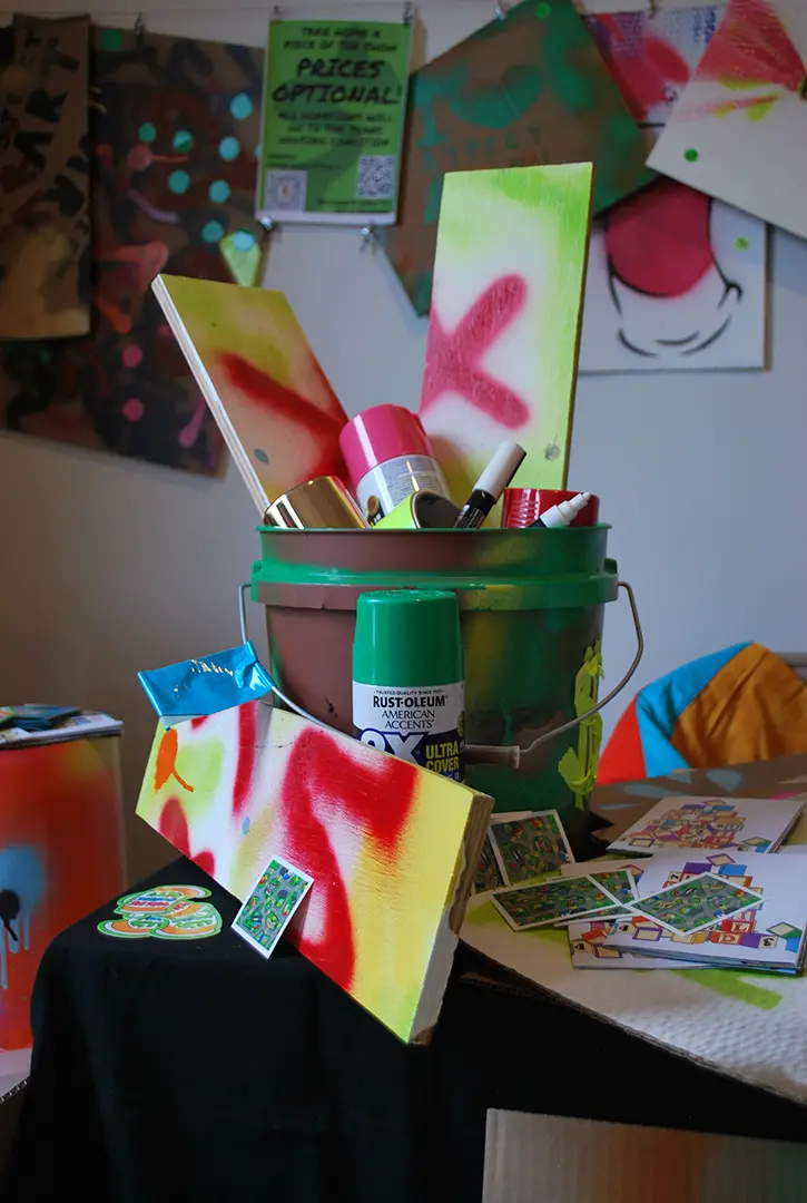 Close up of a bucket filled with wood panels and spray paint on the table.