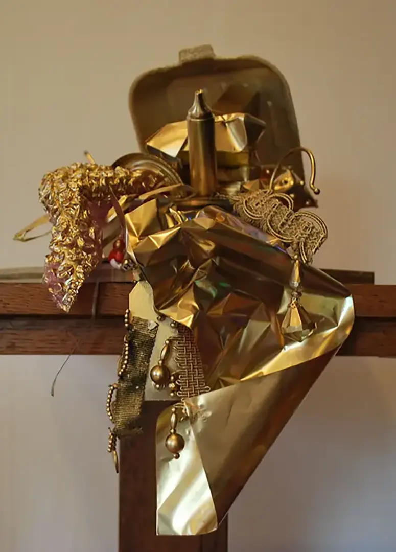 Treasure chest made out of a styrofoam takeout container and filled with trash, spray painted 
                            gold. It's sitting on a wooden pedestal and the contents are spilling over the edge.