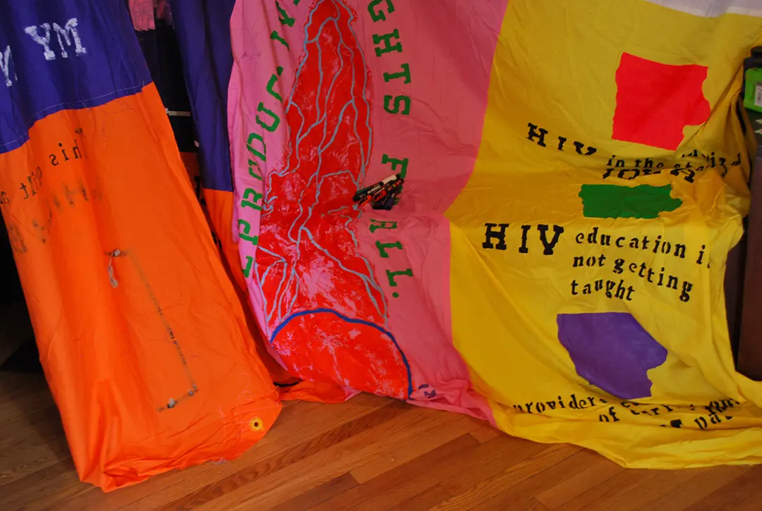 Close up of the bottom of a large hanging AIDS quilt draped over a bench.