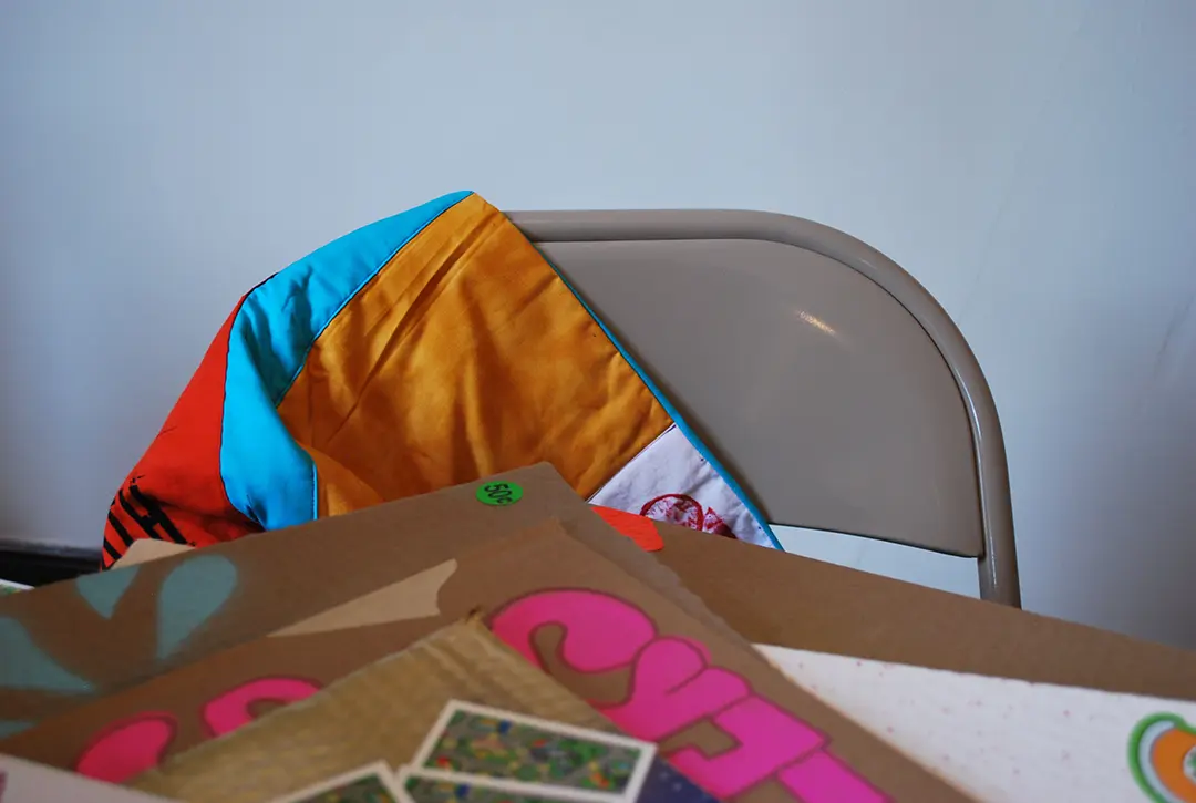 Close up of mini AIDS quilt draped over a folding chair behind the table.