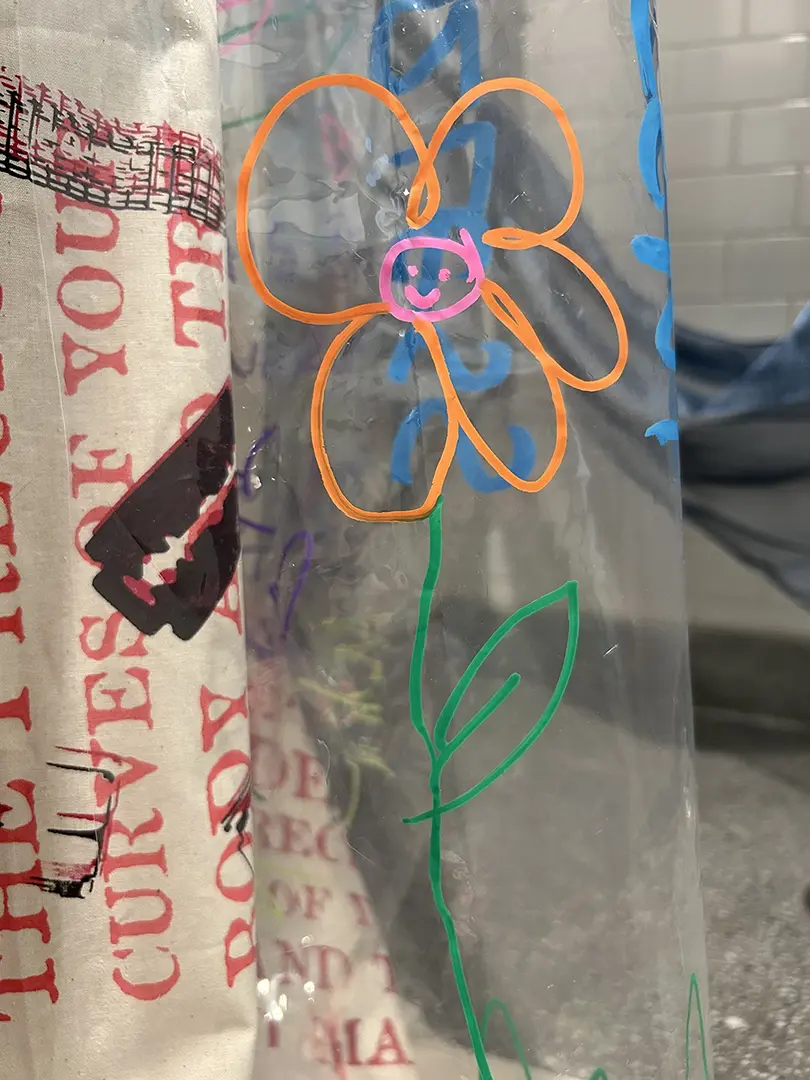 Close up of a doodle of a flower on the clear plastic curtain.