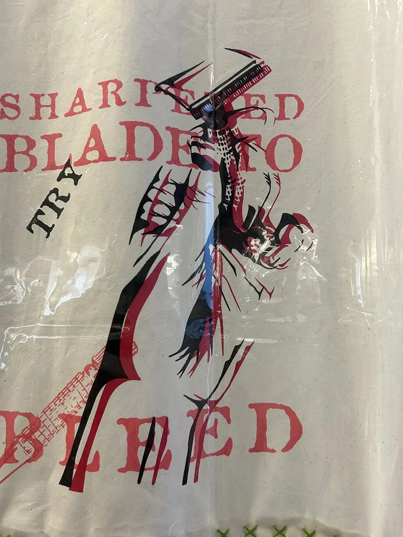 Close up of the curtain. A hand holding a razor blade has been printed over itself, 
                            slightly offset, in red and black