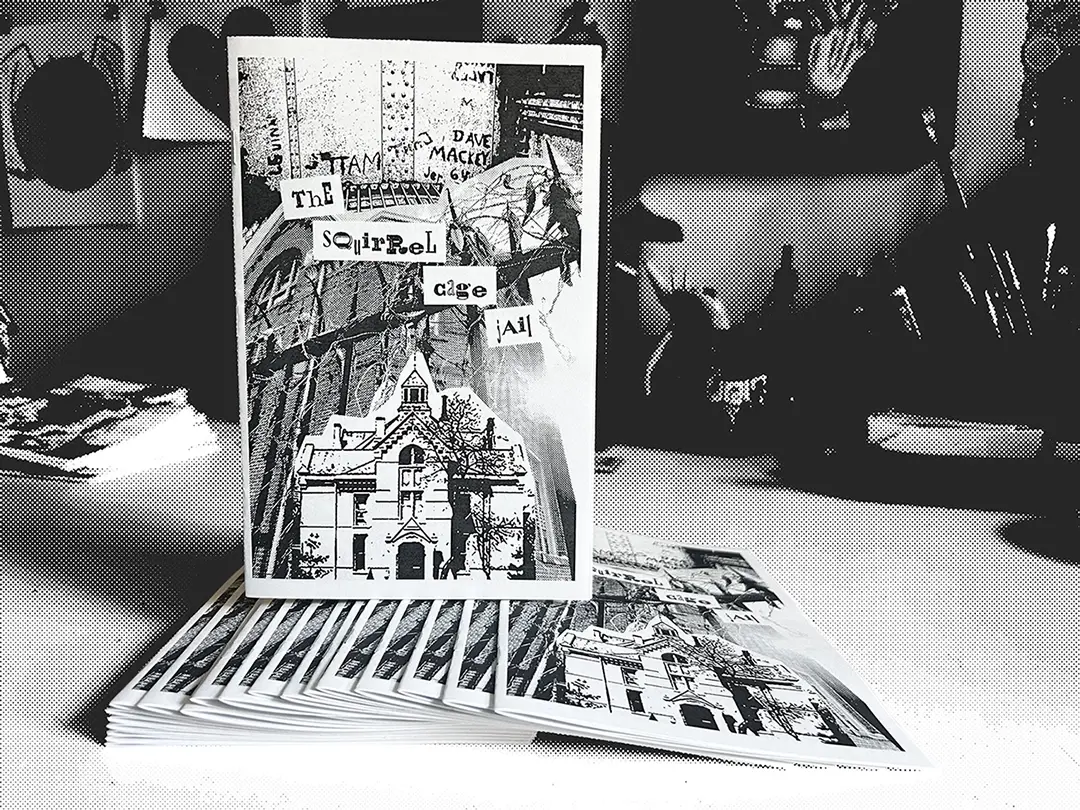 A saddle stitch version of the zine standing on a stack of more zines.